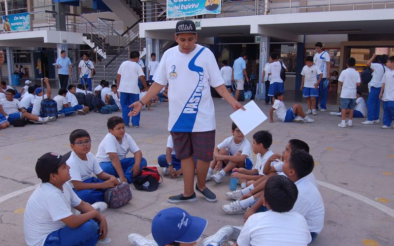 Docente dirigiendo una dinámica con estudiantes sentados en círculo en el patio
