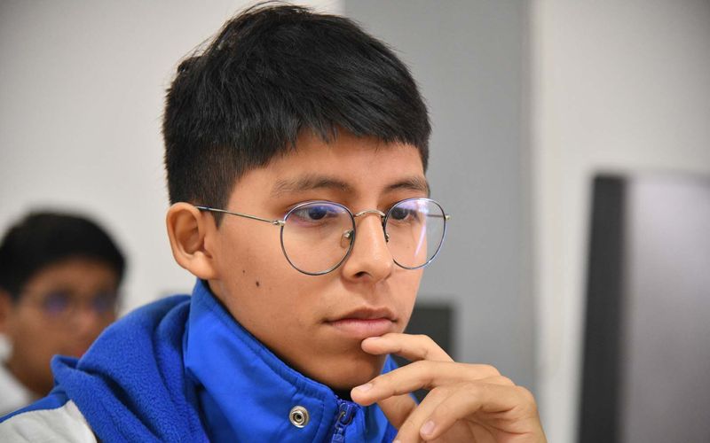 Estudiante de secundaria con la mano en el mentón frente a la pantalla