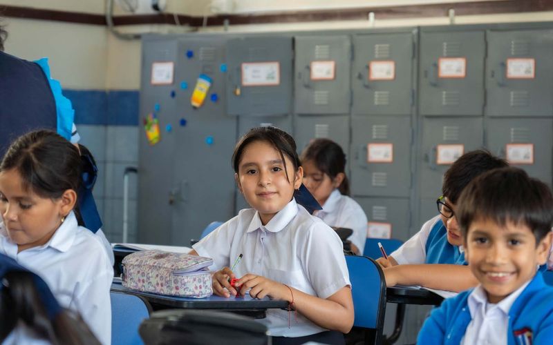 Niños de primaria sonrientes junto a los casilleros del salón