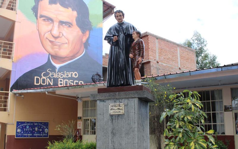 Mural gigante de Don Bosco y estatua en el patio del colegio