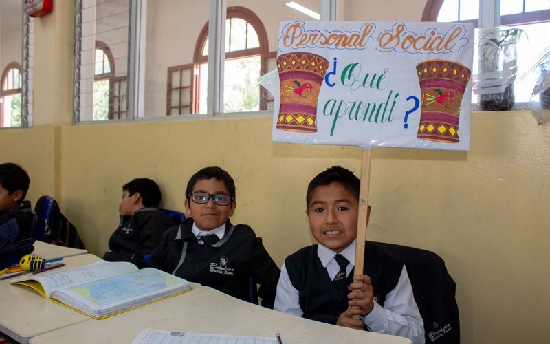 Alumnos sonriendo con el cartel de Personal Social "¿Qué aprendí?" en el aula
