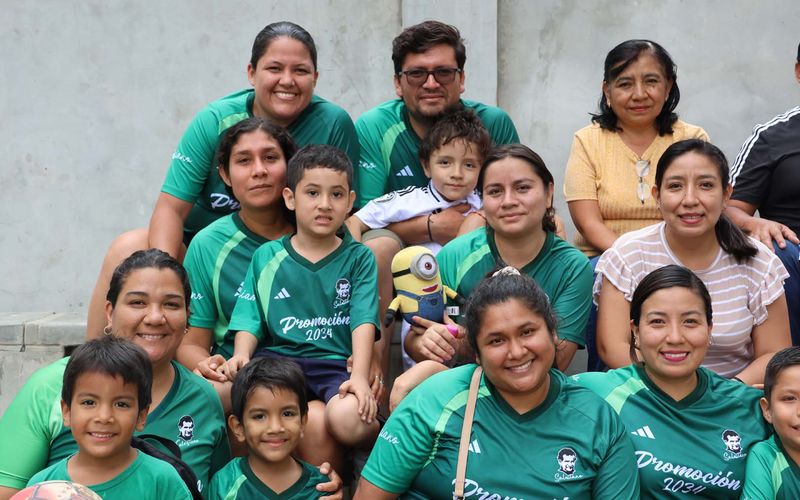Madres, padres e hijos con camisetas verdes de la promoción posando juntos