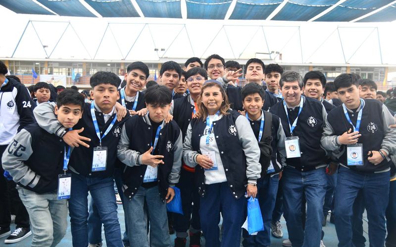 Alumnos de secundaria con casacas del colegio y credenciales posando abrazados y sonrientes