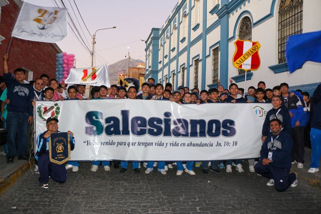Jóvenes con una pancarta que dice «Salesianos» caminan por una calle de Arequipa