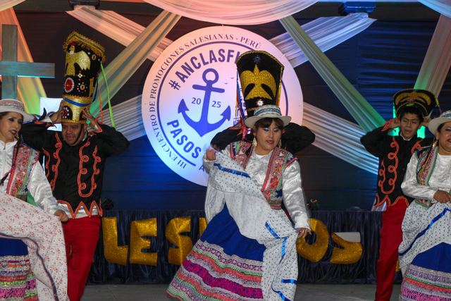 Bailarines con trajes tradicionales frente al logo del encuentro