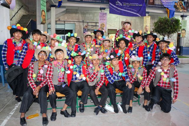 Grupo de jóvenes con sombreros y collares de colores posa sentado
