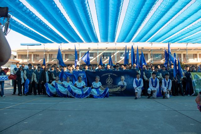 Una delegación posa con su banderola y banderines azules en el patio del colegio