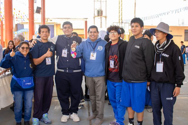 Un grupo de estudiantes y educadores abrazados posa sonriendo en la feria