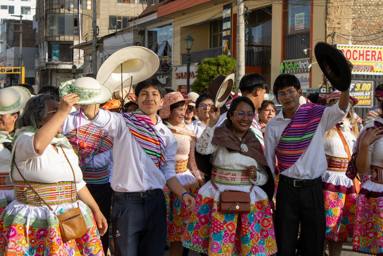 Jóvenes y adultos con trajes típicos bailan en la calle con los sombreros en alto durante la Pasacalle Oratoriana